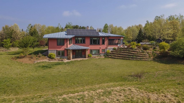 W7429 Akron Dr, Wild Rose, WI 54984 - rear view of house with solar panels, a lawn, metal roof, and a chimney