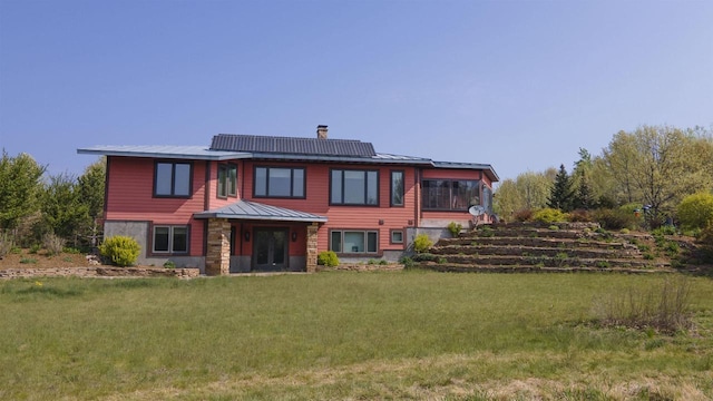 W7429 Akron Dr, Wild Rose, WI 54984 - back of house featuring a lawn, metal roof, a standing seam roof, roof mounted solar panels, and a chimney