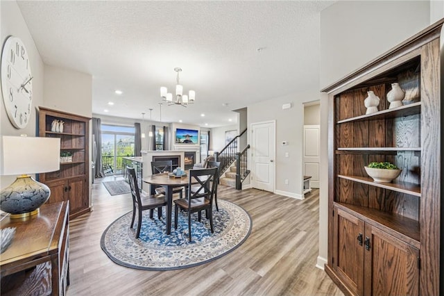 4271 Corn Silk Ln, Saint Paul, MN 55129 - dining area featuring a chandelier, light wood finished floors, baseboards, a textured ceiling, and stairs
