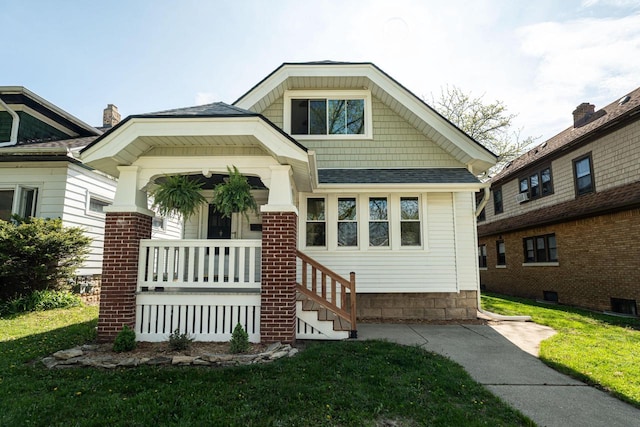 view of front facade with a front lawn, roof with shingles, and central AC