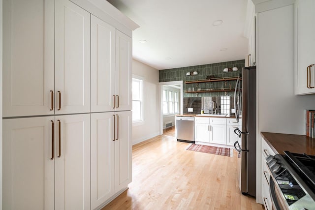 kitchen with appliances with stainless steel finishes, a sink, white cabinetry, light wood finished floors, and recessed lighting