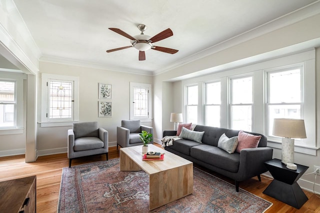 living room featuring light wood finished floors, ornamental molding, a ceiling fan, and baseboards