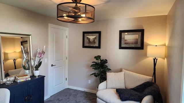 living area featuring dark colored carpet and baseboards