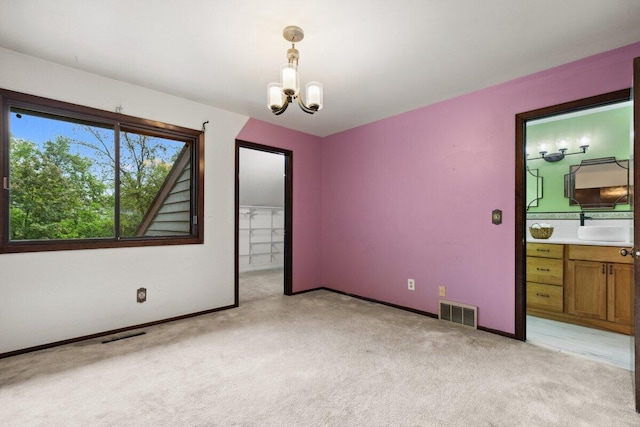 2734 Old Mill Dr Unit A-2, Racine, WI 53405 - unfurnished bedroom with light carpet, a chandelier, baseboards, ensuite bathroom, and a walk in closet