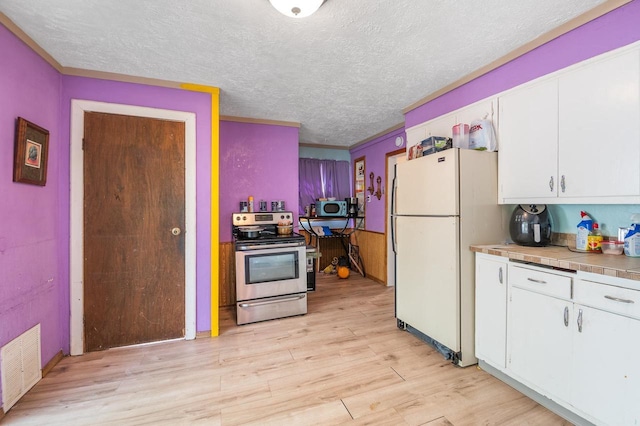 kitchen featuring stainless steel electric stove, freestanding refrigerator, light wood-style flooring, white cabinetry, and a textured ceiling