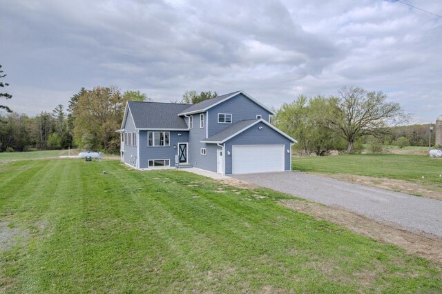 view of front of home with gravel driveway, a front lawn, and a garage
