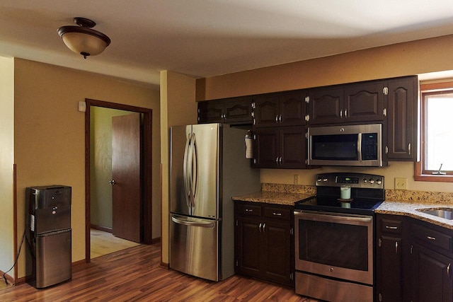 1810 W Upham Ct, Milwaukee, WI 53221 - kitchen featuring appliances with stainless steel finishes, dark wood-style floors, a sink, light stone countertops, and dark brown cabinetry