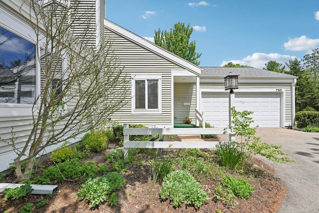 view of front of home featuring a garage, driveway, and roof with shingles