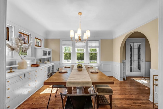 202 Lake Dr, South Milwaukee, WI 53172 - dining room with a chandelier, arched walkways, wainscoting, wood finished floors, and a decorative wall
