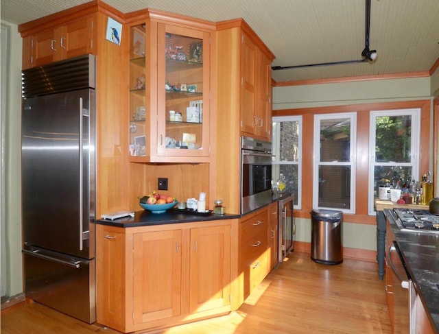 811 Jenifer St, Madison, WI 53703 - kitchen featuring appliances with stainless steel finishes, light wood finished floors, beverage cooler, dark countertops, and ornamental molding