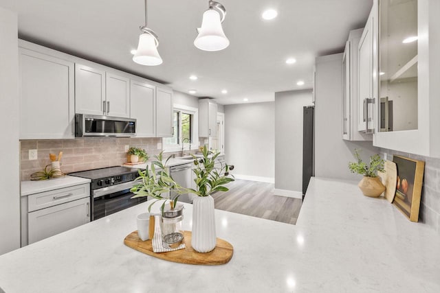 250 W Suburban Ct, Fox Point, WI 53217 - kitchen with appliances with stainless steel finishes, decorative backsplash, light stone counters, recessed lighting, and a sink