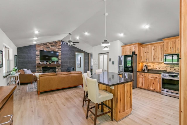 S7698 Grandview Ave, Merrimac, WI 53561 - kitchen with appliances with stainless steel finishes, vaulted ceiling, light wood finished floors, a fireplace, and ceiling fan