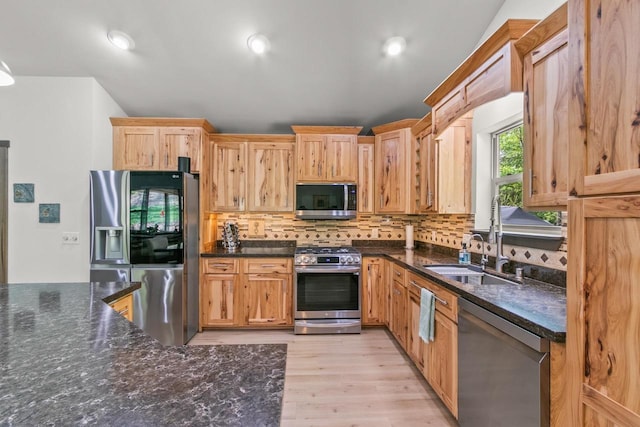 S7698 Grandview Ave, Merrimac, WI 53561 - kitchen featuring appliances with stainless steel finishes, decorative backsplash, light wood-style flooring, dark stone countertops, and a sink