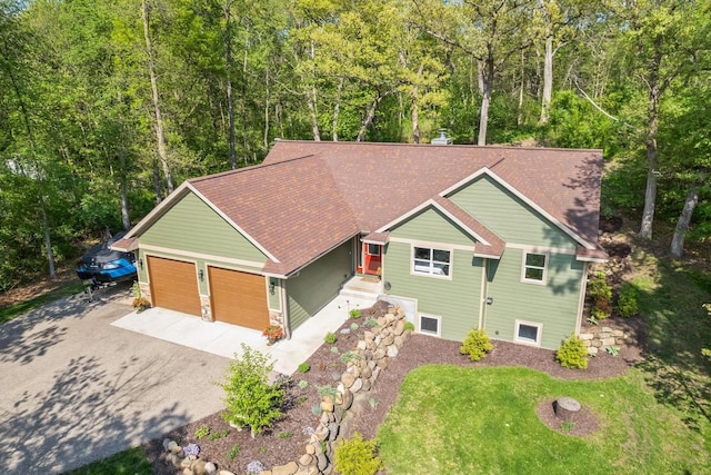 S7698 Grandview Ave, Merrimac, WI 53561 - view of front of house featuring asphalt driveway, a garage, a forest view, and roof with shingles