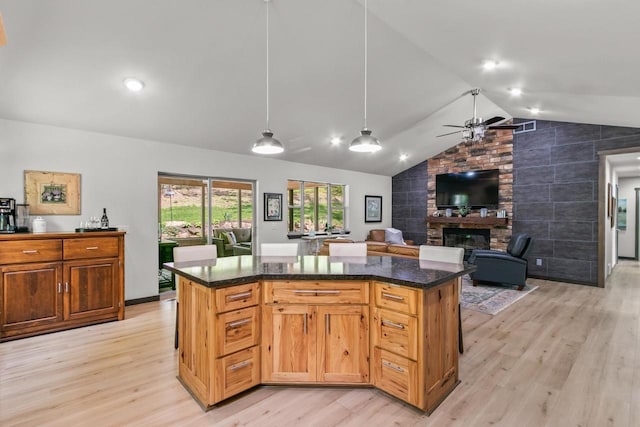 S7698 Grandview Ave, Merrimac, WI 53561 - kitchen featuring vaulted ceiling, light wood finished floors, a large fireplace, a ceiling fan, and a kitchen island