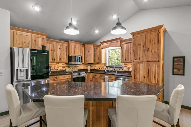 S7698 Grandview Ave, Merrimac, WI 53561 - kitchen featuring stainless steel appliances, lofted ceiling, backsplash, hanging light fixtures, and a kitchen breakfast bar
