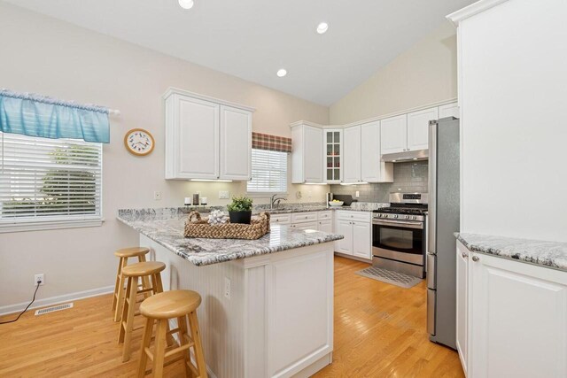 1885 Golfview Dr Unit 35-17, Lake Geneva, WI 53147 - kitchen featuring stainless steel appliances, under cabinet range hood, a peninsula, a kitchen bar, and white cabinetry