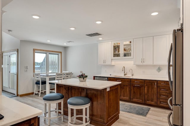 1204 Lakeview Dr # 6, Tomah, WI 54660 - kitchen featuring stainless steel appliances, a sink, white cabinetry, a breakfast bar area, and tasteful backsplash