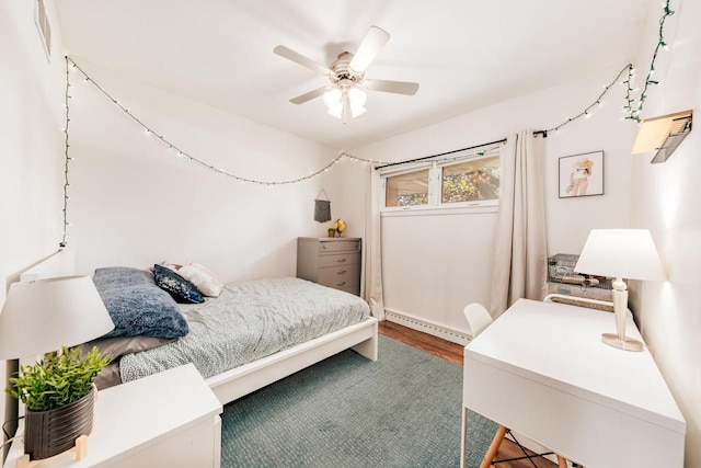 bedroom featuring wood finished floors, baseboard heating, and ceiling fan