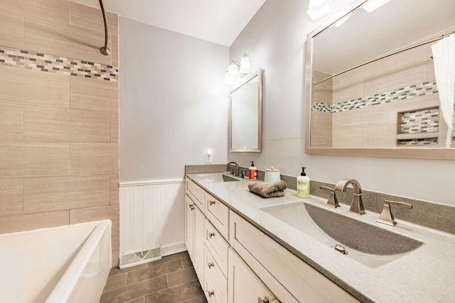 full bathroom with double vanity, tile patterned floors, and wainscoting