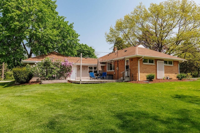 back of house featuring brick siding, a yard, a wooden deck, a chimney, and entry steps