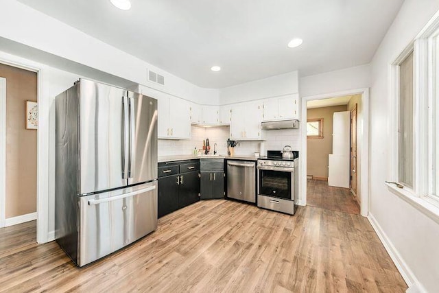 kitchen featuring stainless steel appliances, under cabinet range hood, light wood-style flooring, backsplash, and recessed lighting