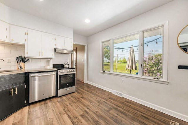 kitchen featuring stainless steel appliances, under cabinet range hood, baseboards, decorative backsplash, and white cabinets
