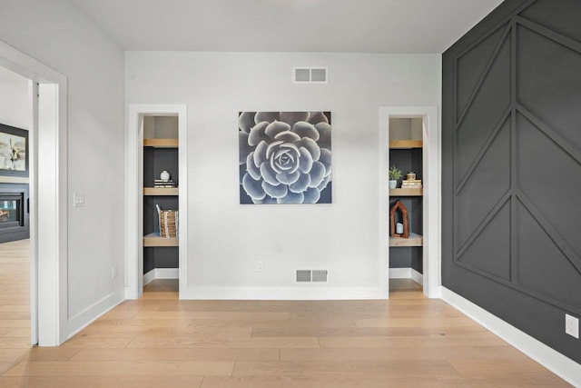 815 Steven Vw, Waunakee, WI 53597 - empty room with light wood-type flooring, built in shelves, baseboards, and a glass covered fireplace