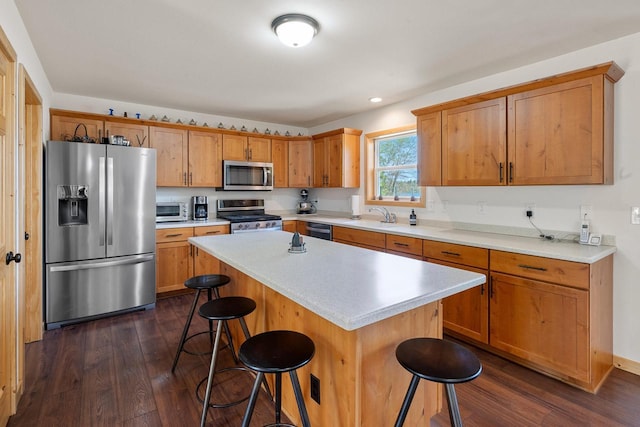12450 Nixon Rd, Minocqua, WI 54548 - kitchen featuring appliances with stainless steel finishes, dark wood-type flooring, a breakfast bar area, a sink, and a kitchen island