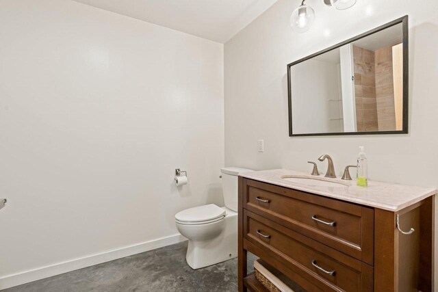 450 Lake Ave, Montello, WI 53949 - bathroom with concrete flooring, vanity, baseboards, and toilet