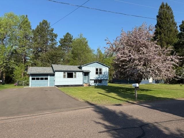 10715 Beal Ave, Hayward, WI 54843 - split level home featuring asphalt driveway, an attached garage, a front yard, and view of wooded area