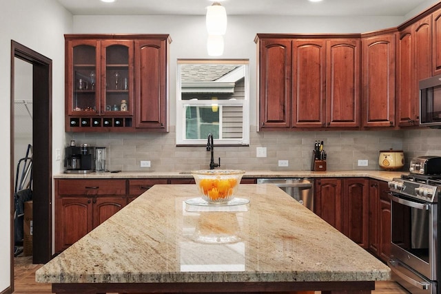 6102 Misty Bridge Rd, Madison, WI 53718 - kitchen with stainless steel appliances, a kitchen island, backsplash, light stone counters, and recessed lighting