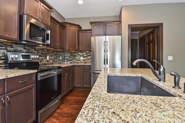 494 Woodfield Cir, Waterford, WI 53185 - kitchen featuring stainless steel appliances, a sink, dark wood-type flooring, light stone counters, and backsplash