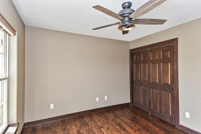 494 Woodfield Cir, Waterford, WI 53185 - unfurnished bedroom featuring dark wood-style floors, baseboards, a ceiling fan, and a closet