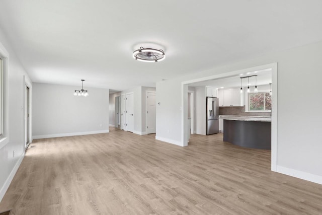 4012 25th Pl, Kenosha, WI 53144 - unfurnished living room featuring light wood finished floors, baseboards, and a chandelier