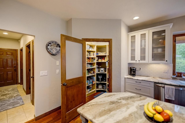 870 Eden Ct, Menasha, WI 54956 - kitchen featuring light stone counters, glass insert cabinets, white cabinets, stainless steel dishwasher, and decorative backsplash