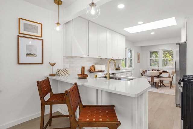 2285 N 166th St, Brookfield, WI 53005 - kitchen with a sink, a peninsula, white cabinetry, a skylight, and light countertops