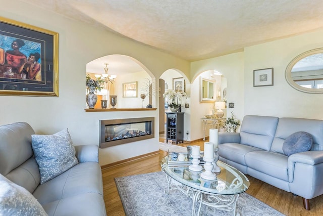 26 Waunona Woods Ct, Madison, WI 53713 - living room with arched walkways, wood finished floors, a chandelier, baseboards, and a glass covered fireplace