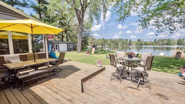 W7660 State Road 21, Wautoma, WI 54982 - deck with outdoor dining area, an outbuilding, a lawn, and a water view