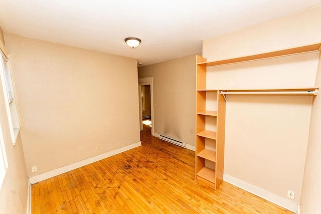 306 Wisconsin St, Oshkosh, WI 54901 - unfurnished bedroom with a baseboard heating unit, light wood-style floors, baseboards, and a baseboard radiator