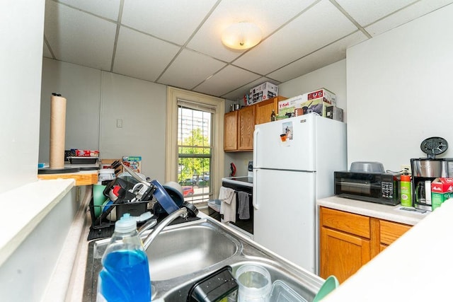 306 Wisconsin St, Oshkosh, WI 54901 - kitchen with freestanding refrigerator, a paneled ceiling, brown cabinets, and light countertops