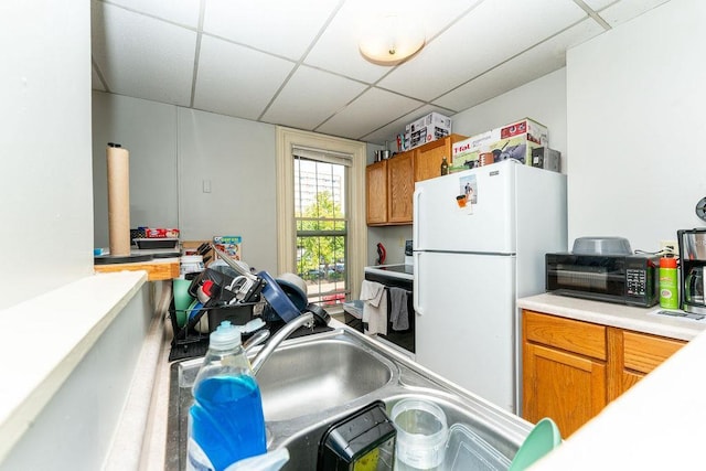 306 Wisconsin St, Oshkosh, WI 54901 - kitchen featuring a paneled ceiling, freestanding refrigerator, brown cabinets, range with electric stovetop, and light countertops