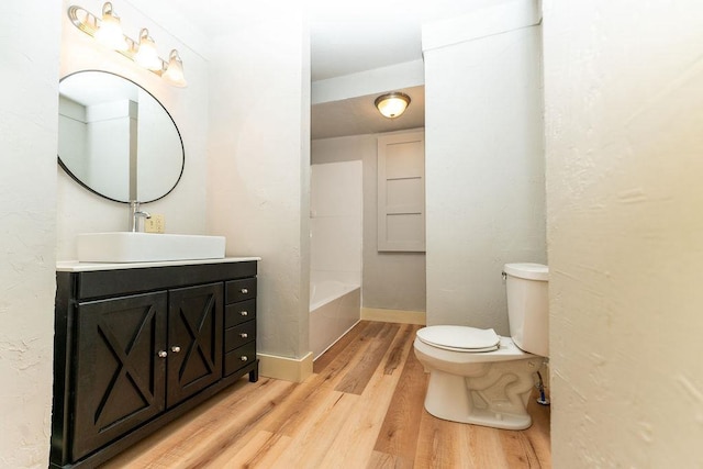 306 Wisconsin St, Oshkosh, WI 54901 - bathroom with wood finished floors, toilet, a bath, vanity, and baseboards