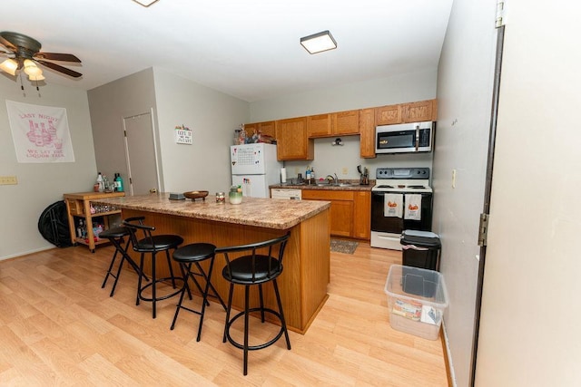 306 Wisconsin St, Oshkosh, WI 54901 - kitchen with white appliances, a sink, light wood-type flooring, a ceiling fan, and a kitchen bar
