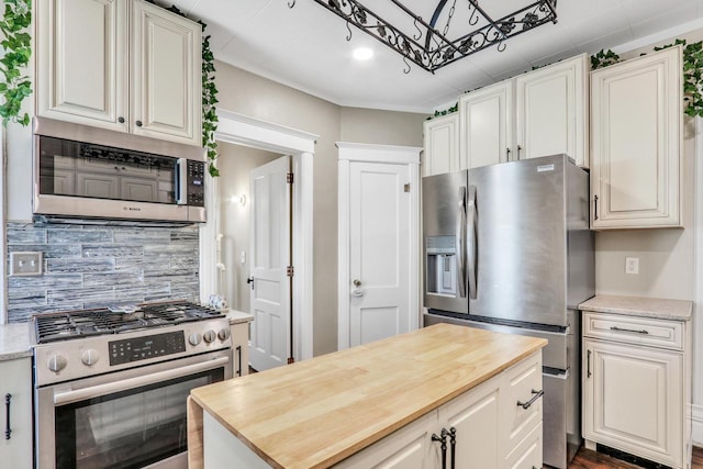 822 12th Ave, Union Grove, WI 53182 - kitchen featuring appliances with stainless steel finishes, wooden counters, backsplash, white cabinetry, and a kitchen island