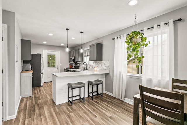 632 Grove St, Portage, WI 53901 - kitchen featuring stainless steel appliances, wood finished floors, a peninsula, light countertops, and a breakfast bar area