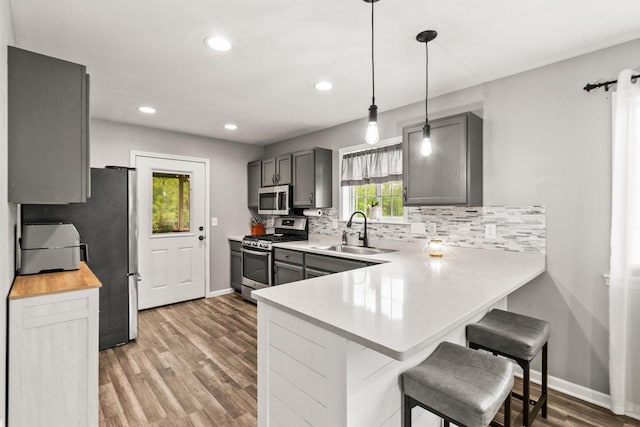 632 Grove St, Portage, WI 53901 - kitchen featuring appliances with stainless steel finishes, a sink, decorative backsplash, a breakfast bar area, and light wood-style floors