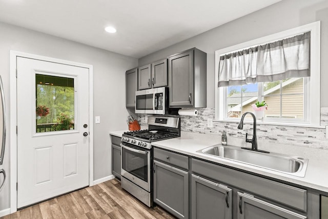 632 Grove St, Portage, WI 53901 - kitchen featuring stainless steel appliances, gray cabinetry, a sink, light wood finished floors, and backsplash