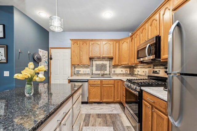226 N Main St Unit 6, Walworth, WI 53184 - kitchen with stainless steel appliances, a sink, light wood finished floors, decorative backsplash, and dark stone countertops