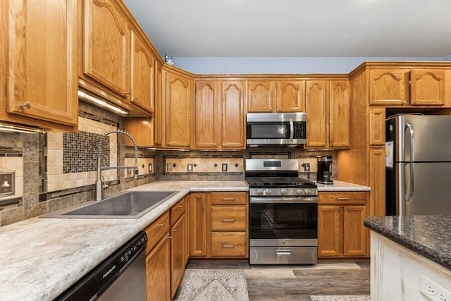 226 N Main St Unit 6, Walworth, WI 53184 - kitchen with stainless steel appliances, a sink, decorative backsplash, light wood-style flooring, and brown cabinets